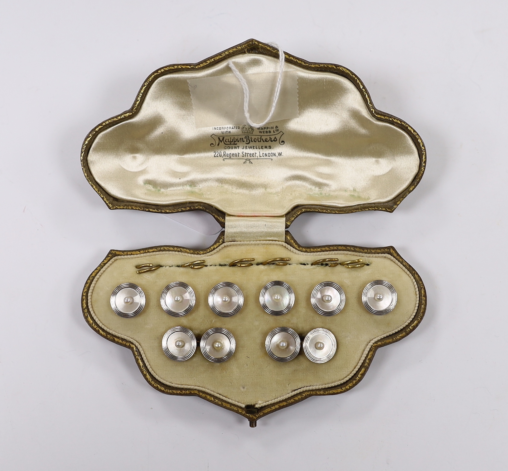 An early to mid 20th century 18ct, mother of pearl and seed pearl set eight piece dress stud set, including pair of cufflinks and six buttons, in fitted gilt tooled leather box by Mappin Brothers, gross weight 17.4 grams